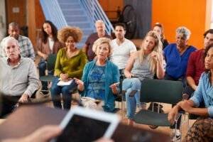 Woman Speaking At Group Neighborhood Meeting In Community Center