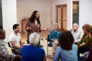 Woman Standing To Address Self Help Therapy Group Meeting In Community Center